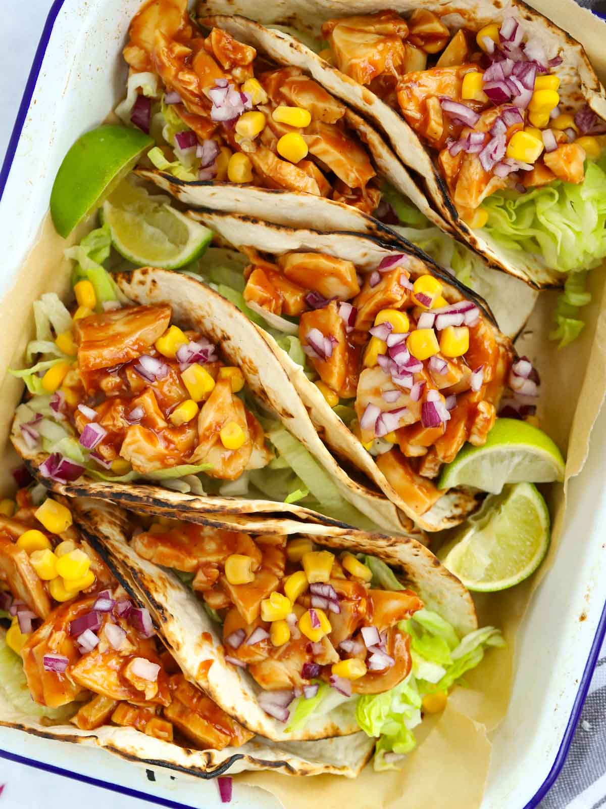 Chicken and brace tacos filled with lettuce, sweetcorn and red onion