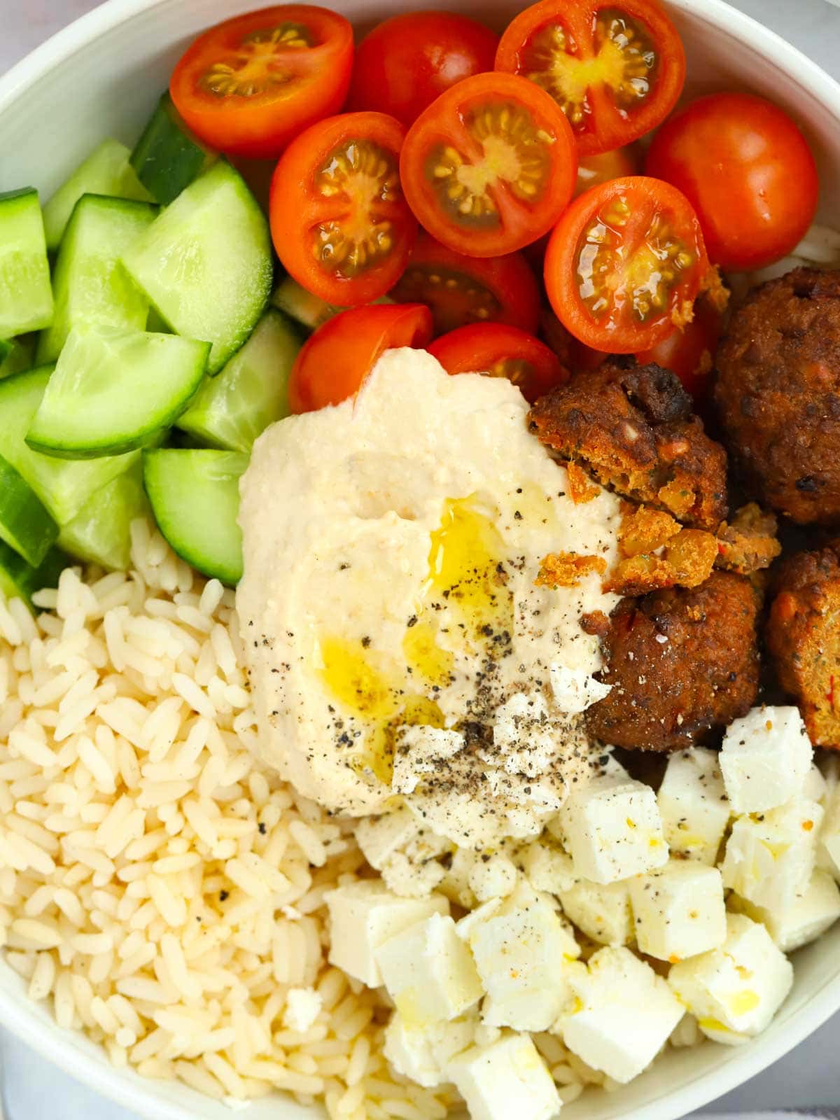 Light Hummus Salad Bowl meal containing rice, hummus, feta cheese, falafel, cucumber and tomato 