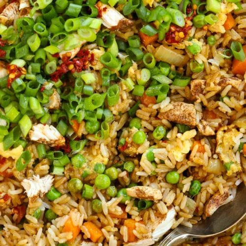 Close up of egg fried rice with chicken and vegetables, sprinkled with spring onions and chilli
