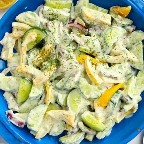 Bowlful of cucumber salad with yellow pepper, red onion and natural yoghurt dressing with dill and garlic