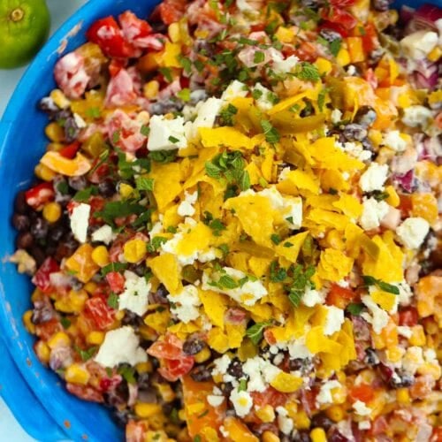 A bowl of salad ingredients making up a colourful Mexican Salad topped with tortilla chips