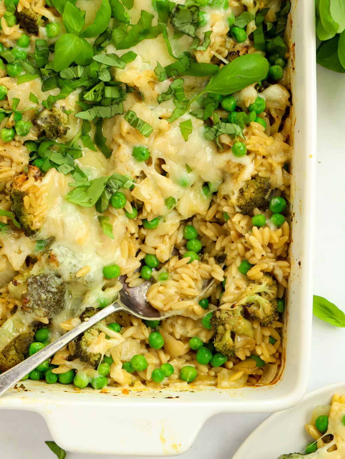 A dish with broccoli, orzo and peas, topped with melted cheese