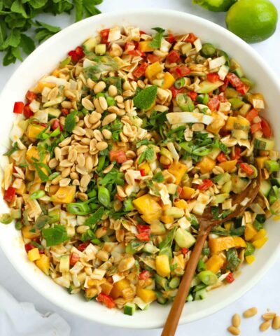 A big bowl of salad with peanut butter dressing, peppers, cabbage and mango
