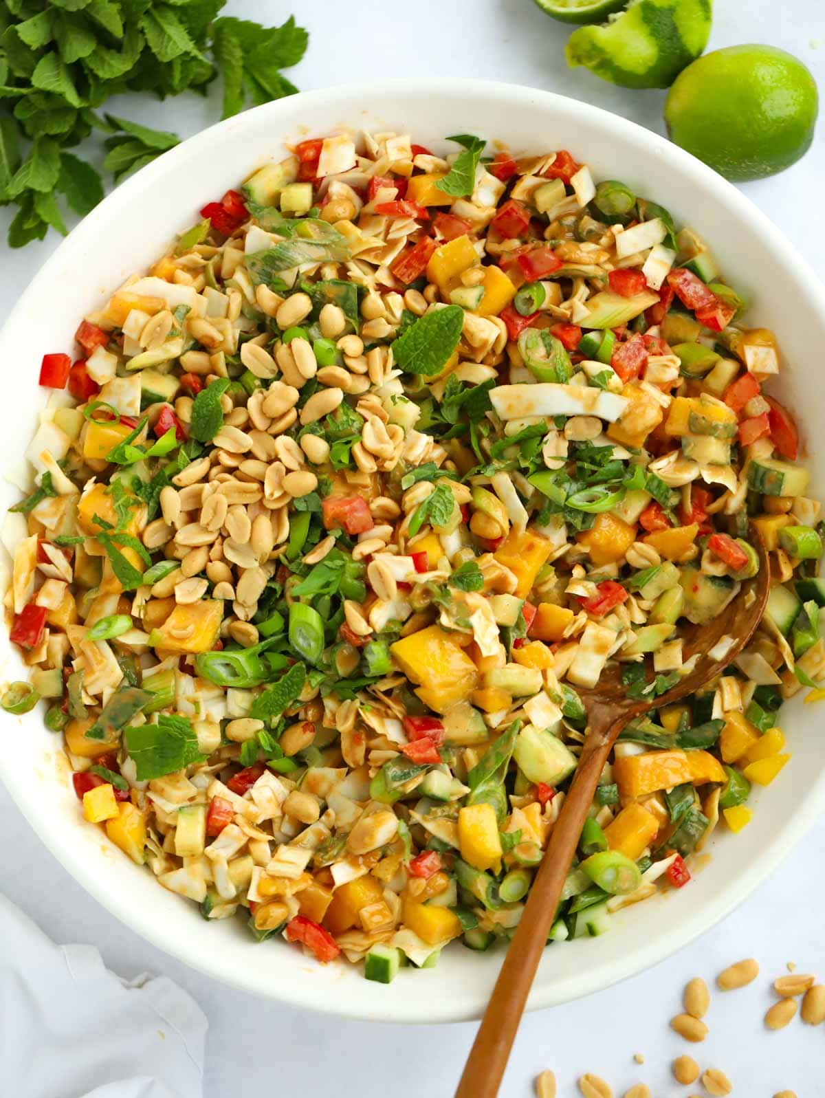 A big bowl of salad with peanut butter dressing, peppers, cabbage and mango