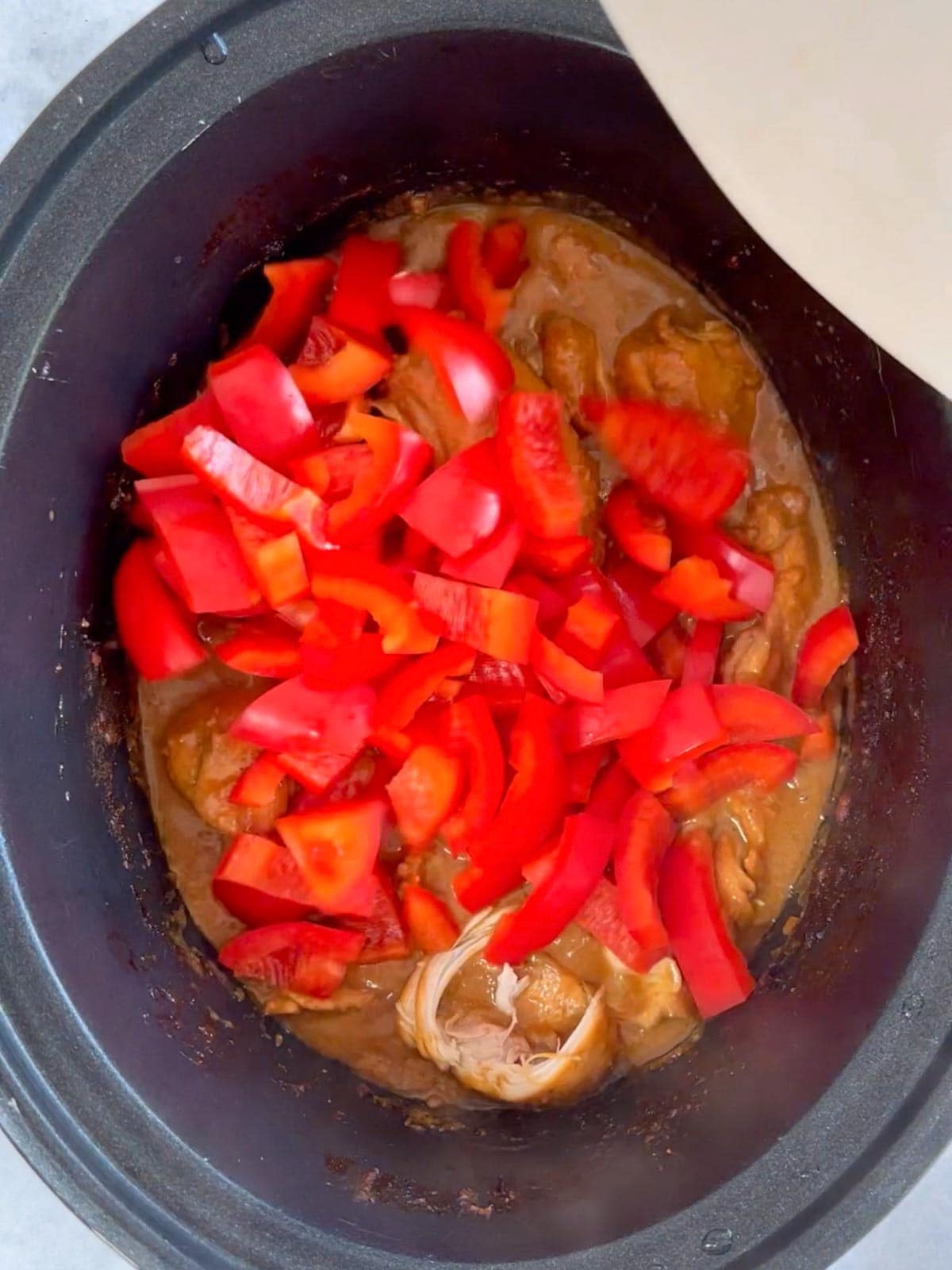 Step 2 in the recipe for Slow Cooker Chicken Satay. Add ingredients to the pan.