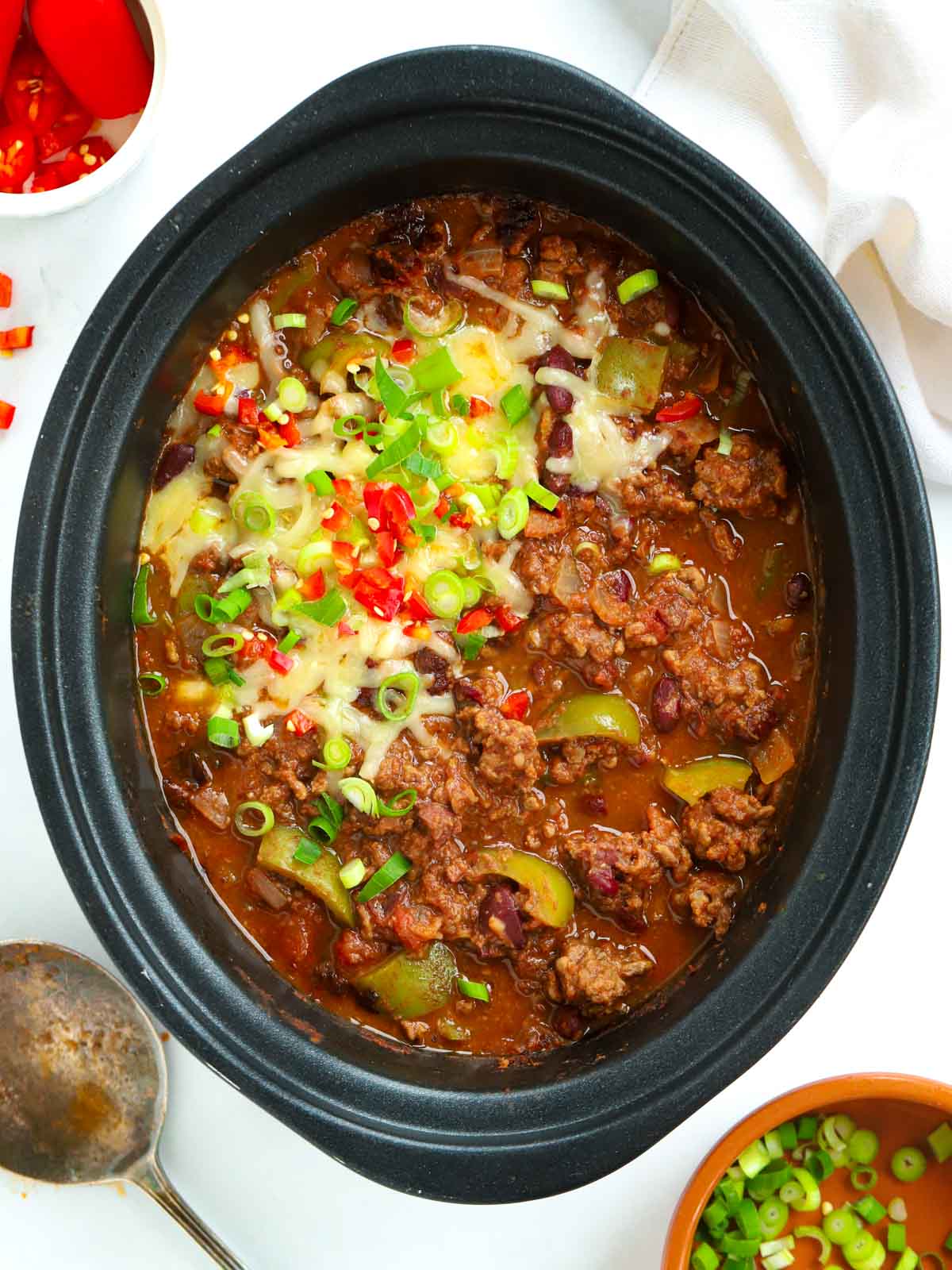 Slow cooker Chilli Con Carne topped with cheese and chillis after it has finished cooking.