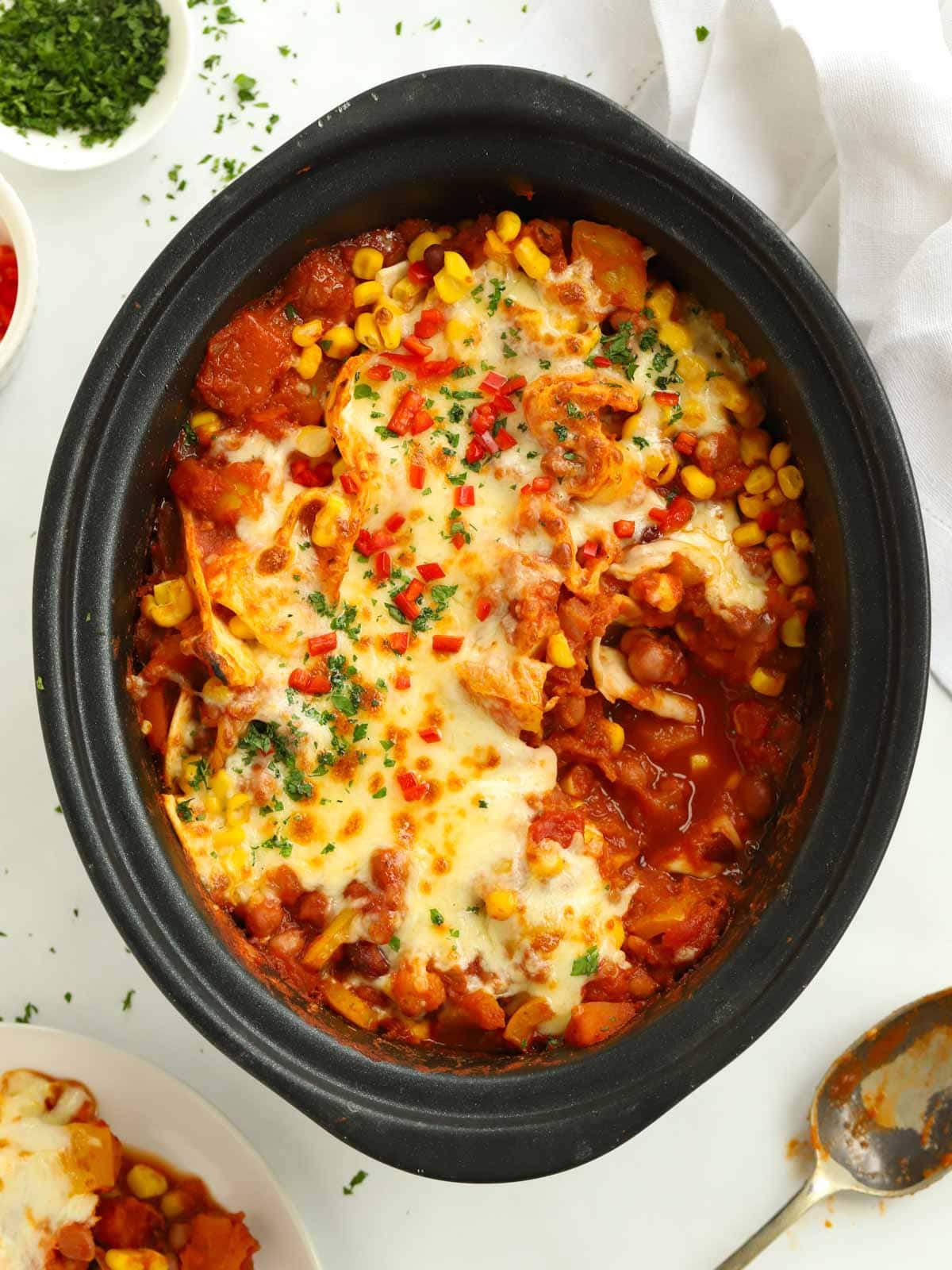 Slow cooker pot filled with veggie enchiladas, cooked and topped with cheese.