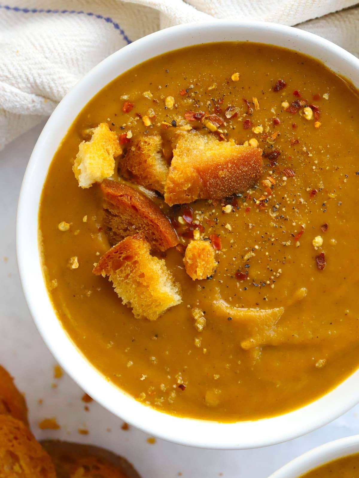 Close up of a bowl of roasted butternut squash soup topped with croutons.