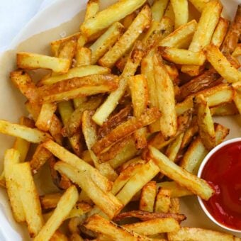 A plate of healthy homemade oven chips with ketchup on the side.