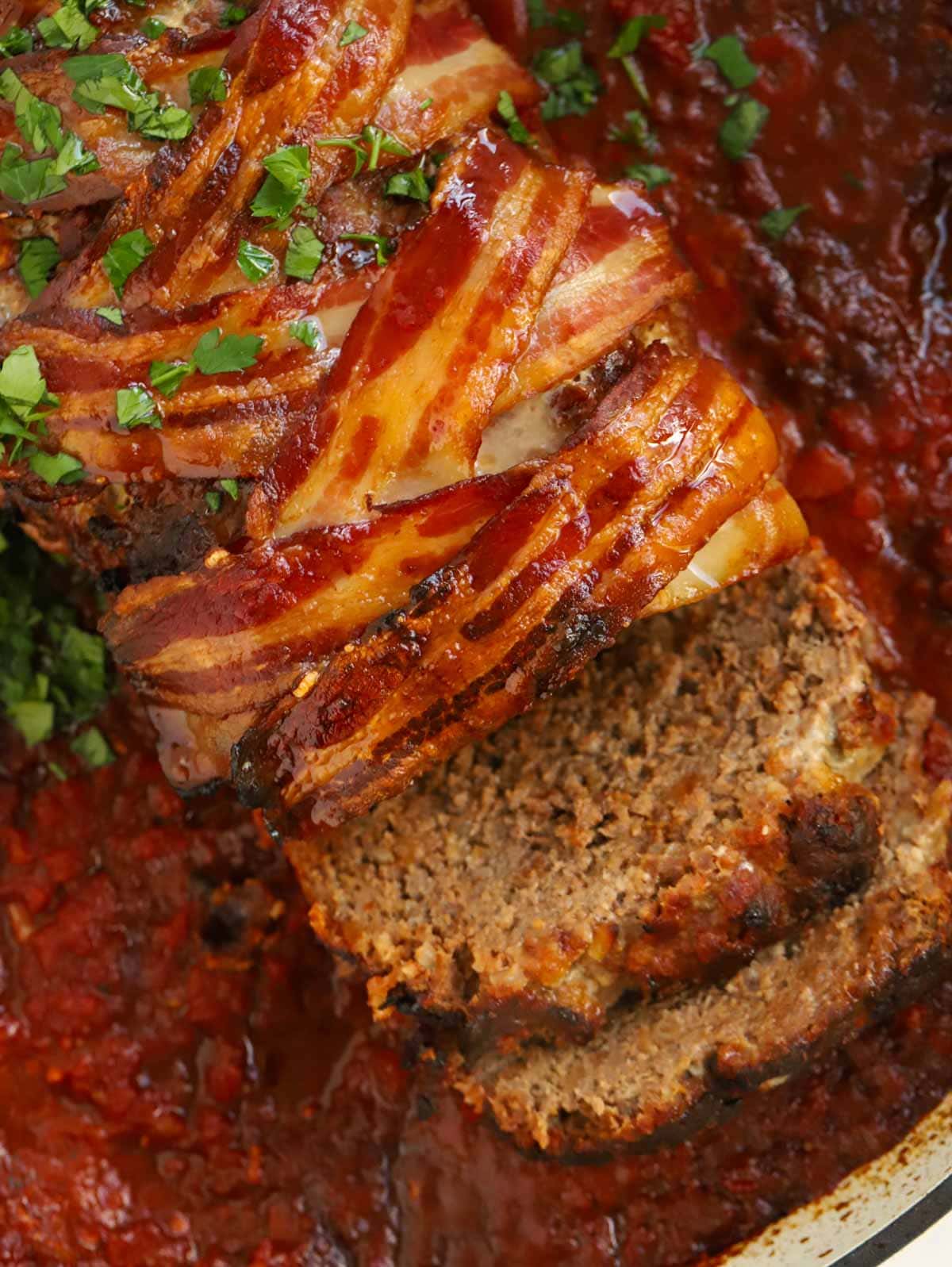 Finished meatloaf out of the oven in a rich sauce and topped with crispy bacon.