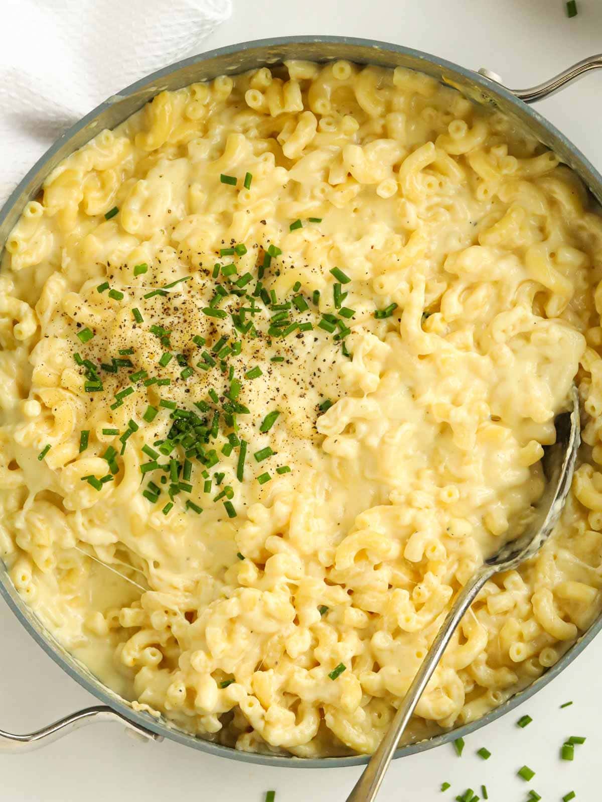 Big pan full of cooked simple Macaroni Cheese, topped with chives.