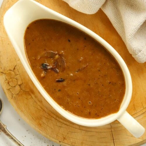 A gravy boat filled with delicious red onion gravy for a how-to guide in how to make onion gravy.