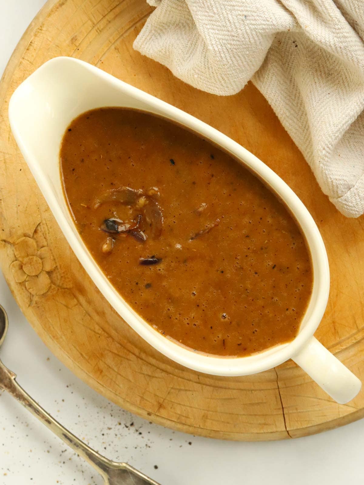 A gravy boat filled with delicious red onion gravy for a how-to guide in how to make onion gravy.