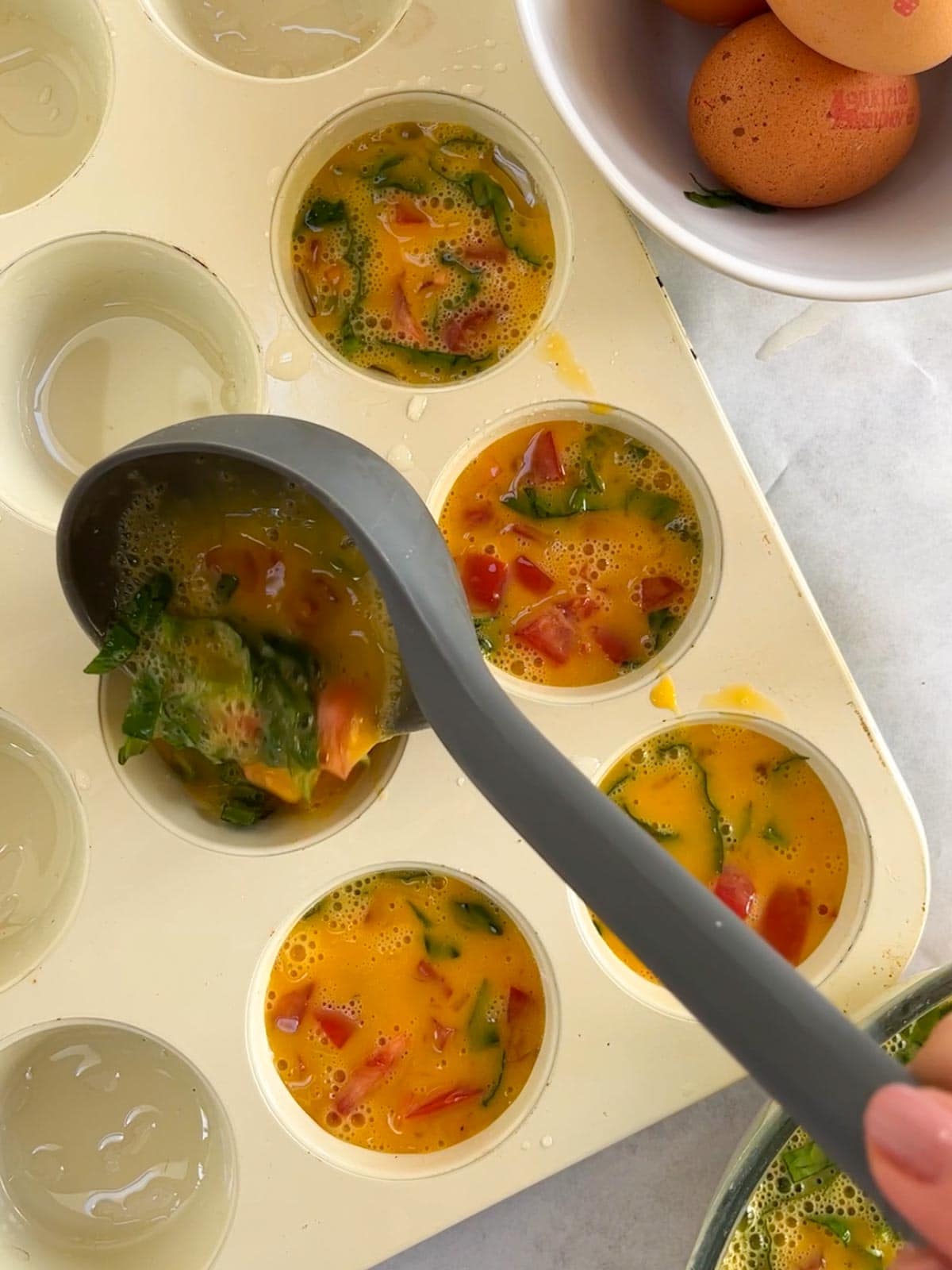 Cooking egg muffins with spinach and tomato in the oven.