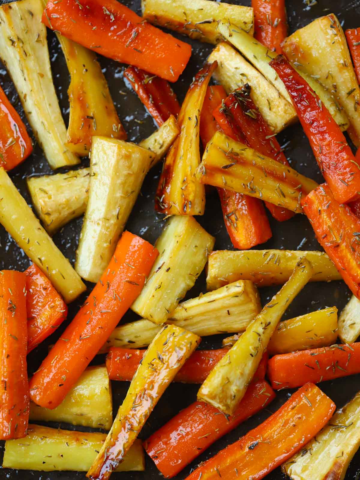 Honey Roasted Carrots and Parsnips on a tray, sprinkled with thyme.