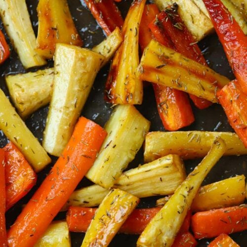Colourful carrots and parsnips on a baking tray and roasted with honey and thyme.