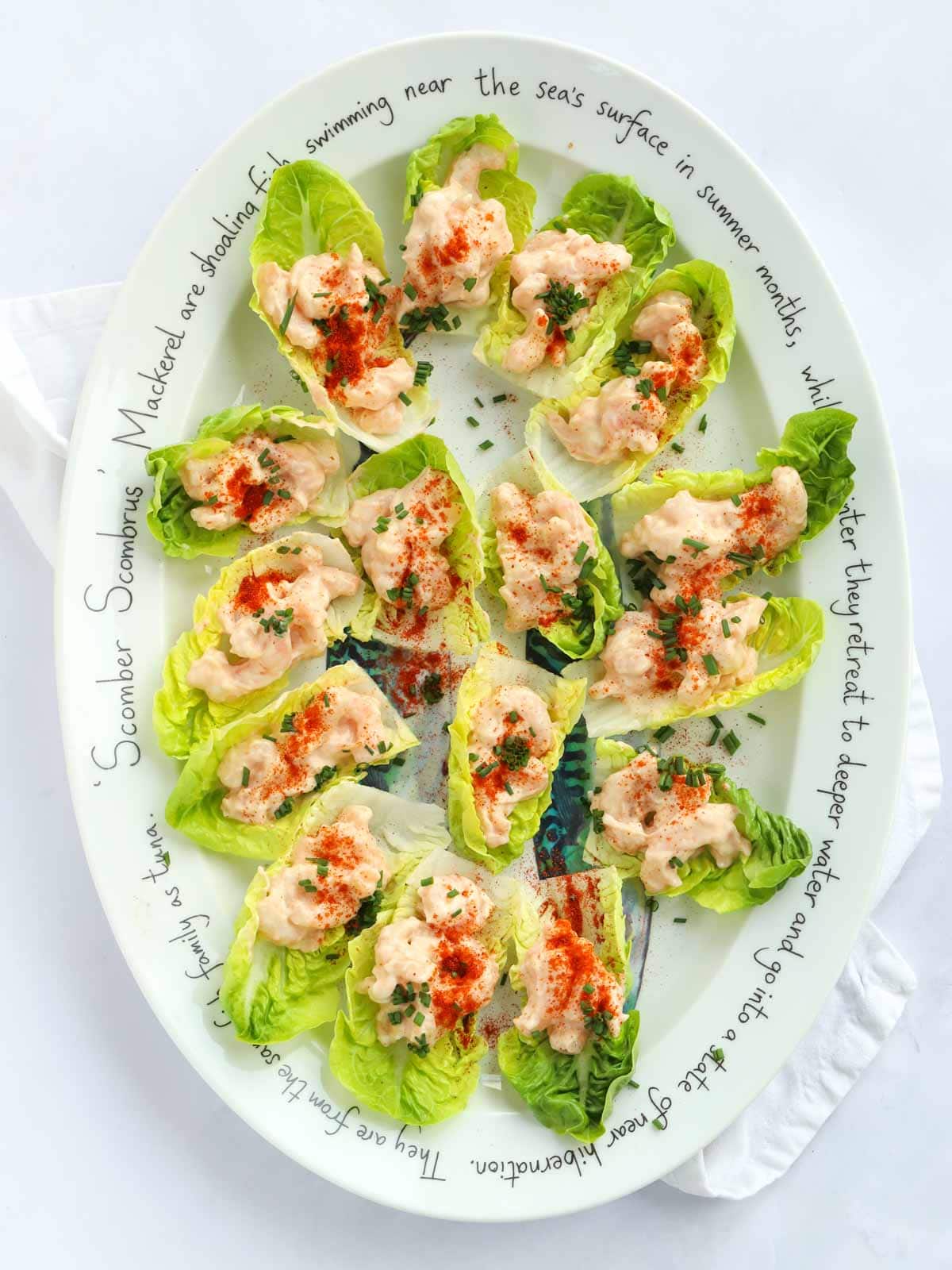 A large platter filled with prawn cocktail canapés on a bed of little gem lettuce leaf cups.