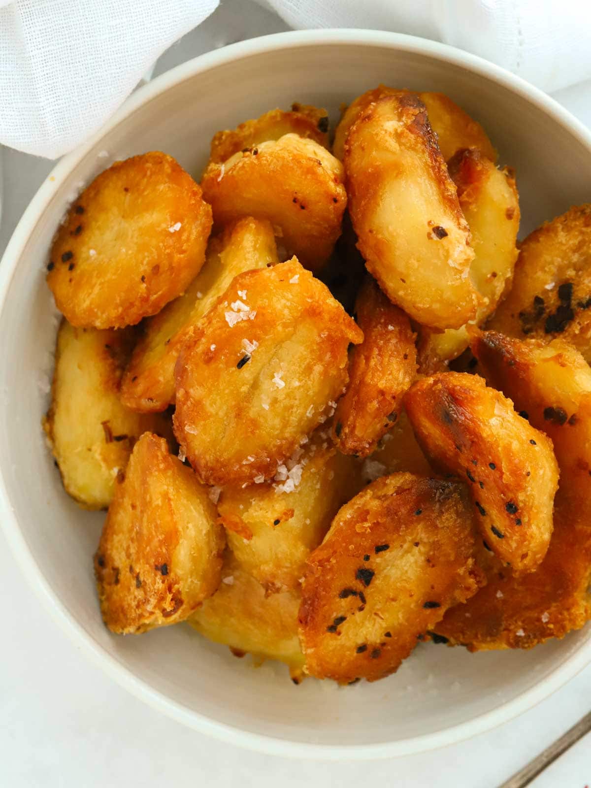 Close up of a bowl of delicious golden roast potatoes. This is an easy recipe.