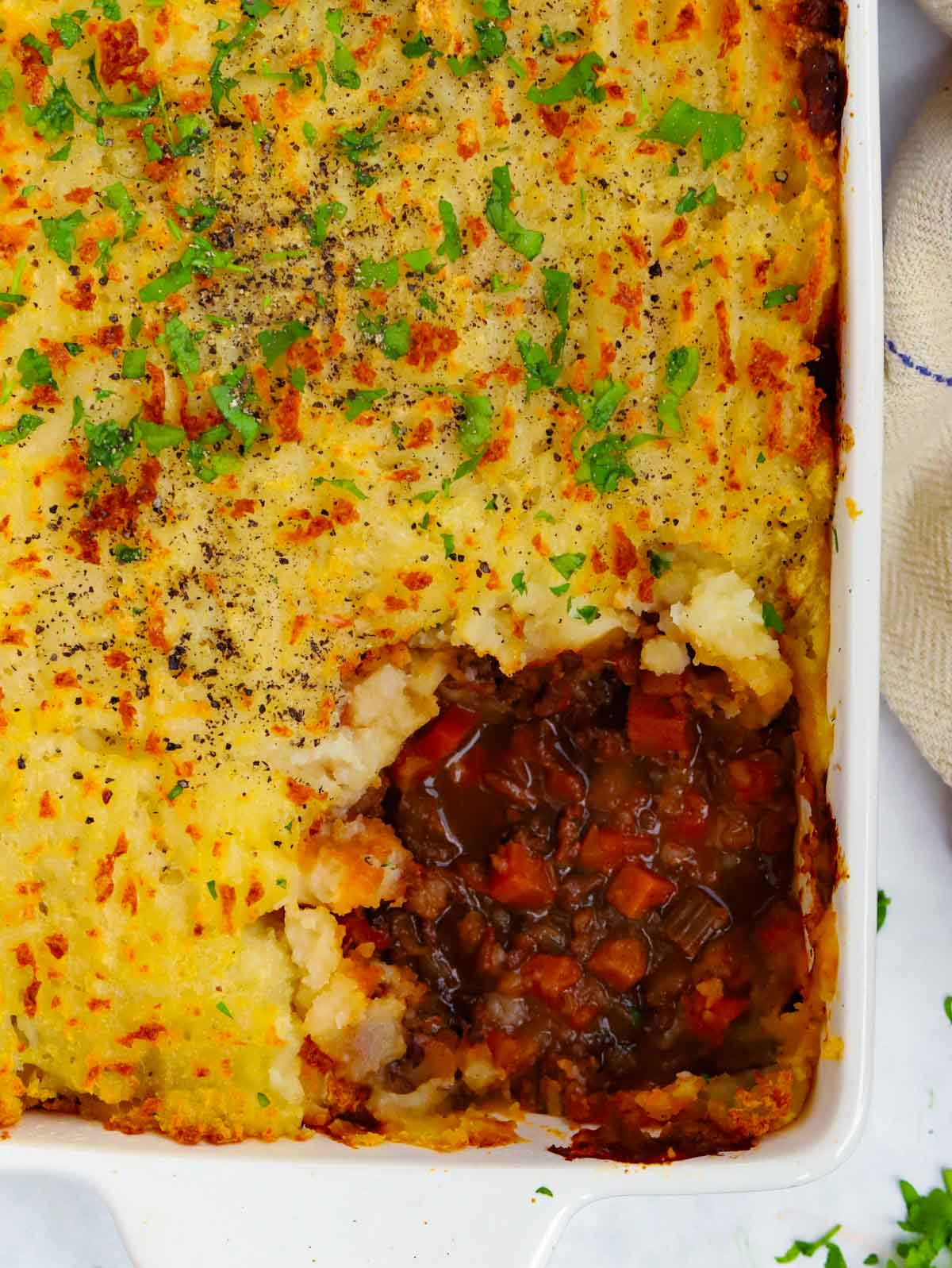 Classic, simple Shepherd's Pie straight out of the oven with corner portion missing.