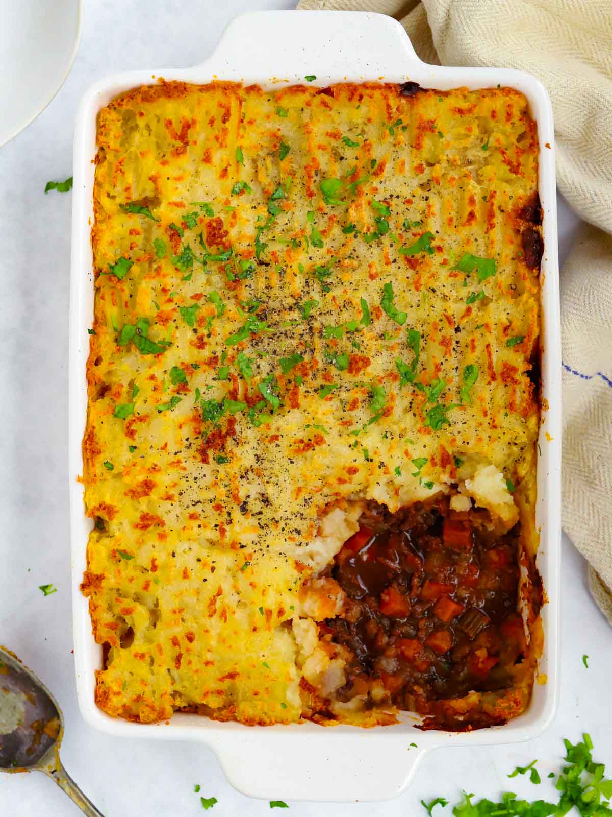 Big cooked shepherd's pie with portion missing.