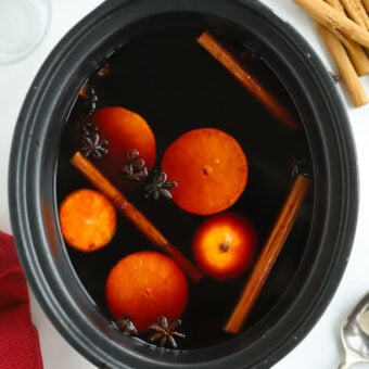 Recipe for Slow Cooker Mulled Wine cooking with orange slices, cinnamon sticks and star anise.