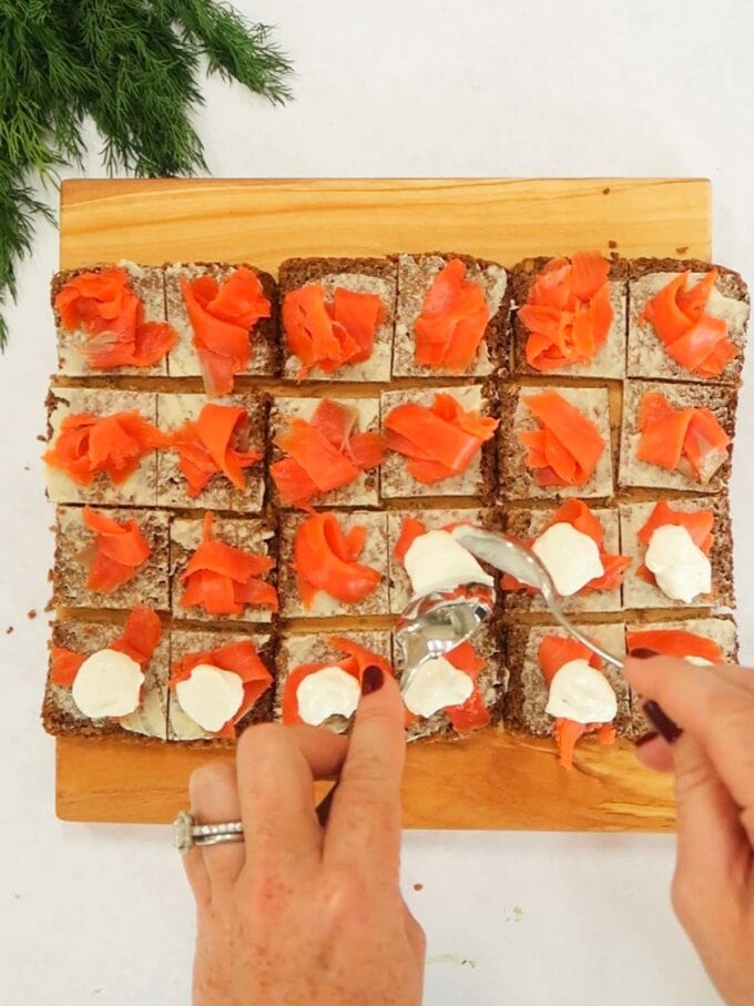 How to make Smoked Salmon Canapés step 2. Add salmon and sauce to rye bread squares.