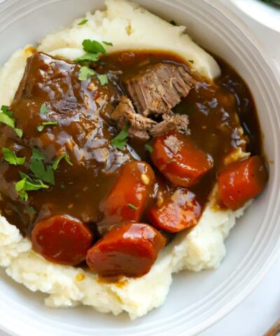Delicious braised steak with carrots in gravy over a bed of mashed potato.