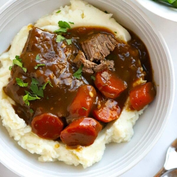 Delicious braised steak with carrots in gravy over a bed of mashed potato.