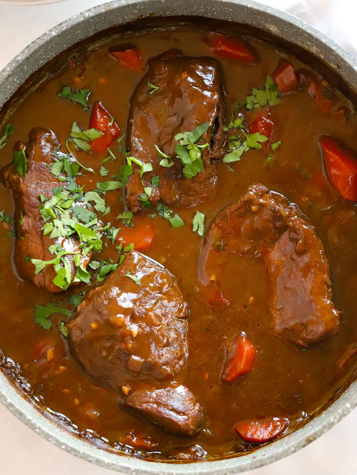 Close up of a pan of cooked braised steak, ready to be served up.