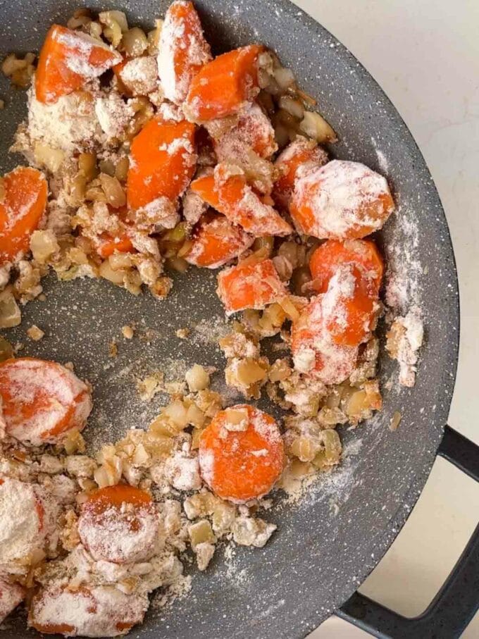 Step 3 in the recipe for Braised Steak. Carrots and onion in a pan with flour sprinkled over the top.