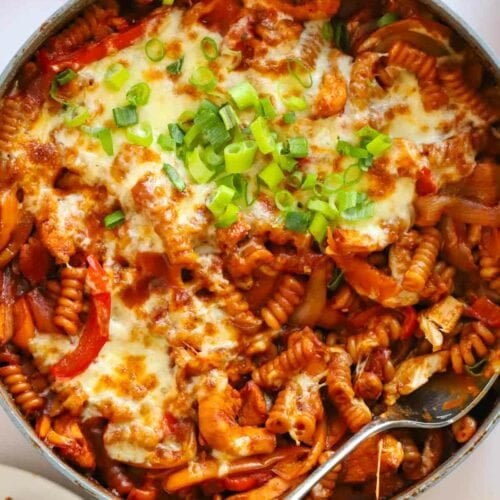 Double handed large pan with spoon dipped into a pan full of Chicken Fajita Pasta.