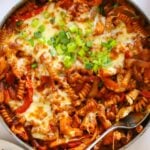 Big pan full of Chicken Fajita Pasta Bake with cheese and spring onion on top.