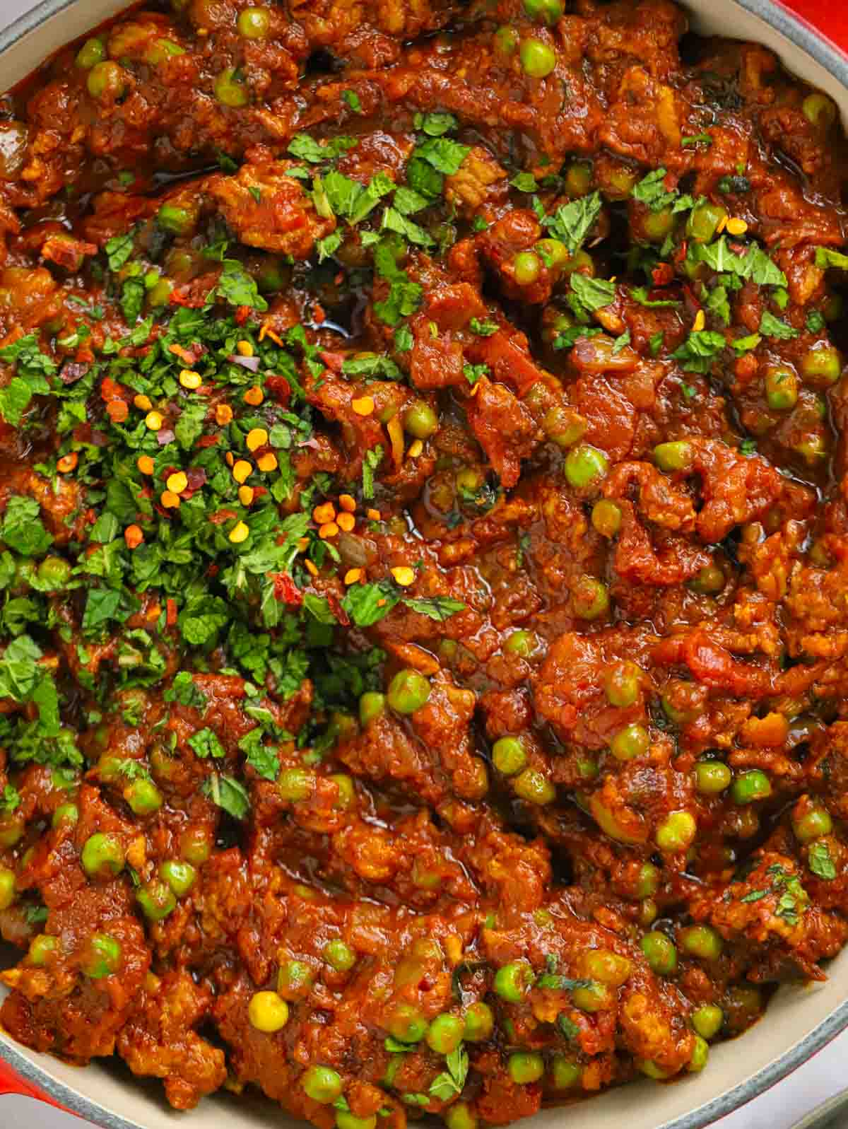 Close up of lamb keema curry with peas in a big pan.