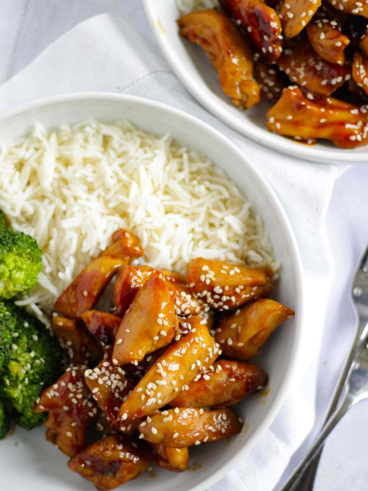 Full meal of teriyaki chicken and rice and broccoli laid on a table.