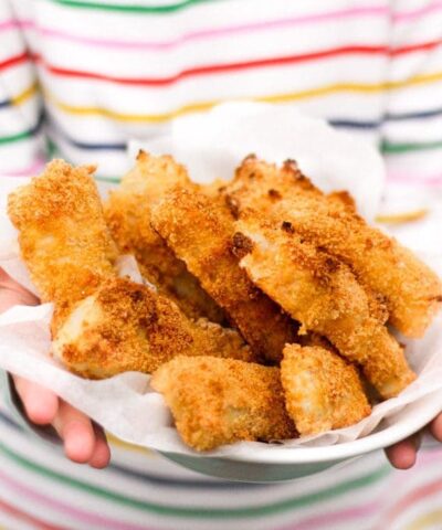 Homemade fish fingers being held on a plate.
