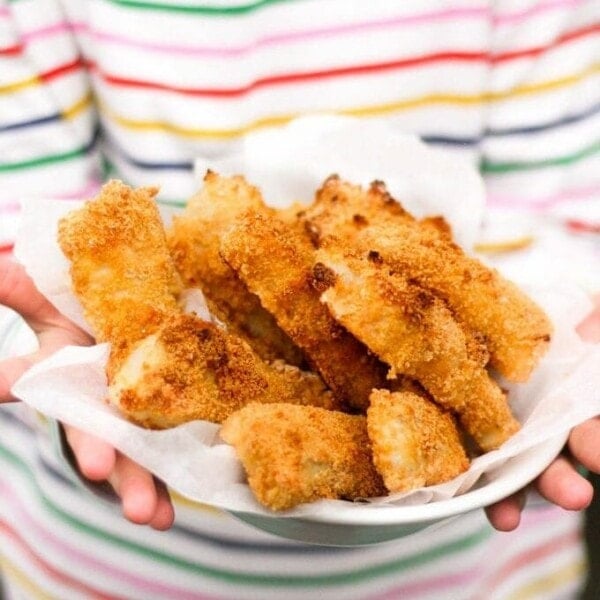 Homemade fish fingers being held on a plate.