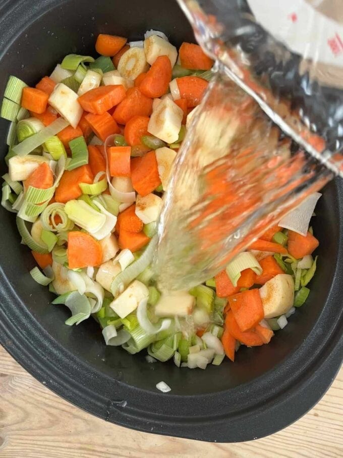 Step 1 in the process of how to make slow cooker vegetable soup. Add ingredients and stock.
