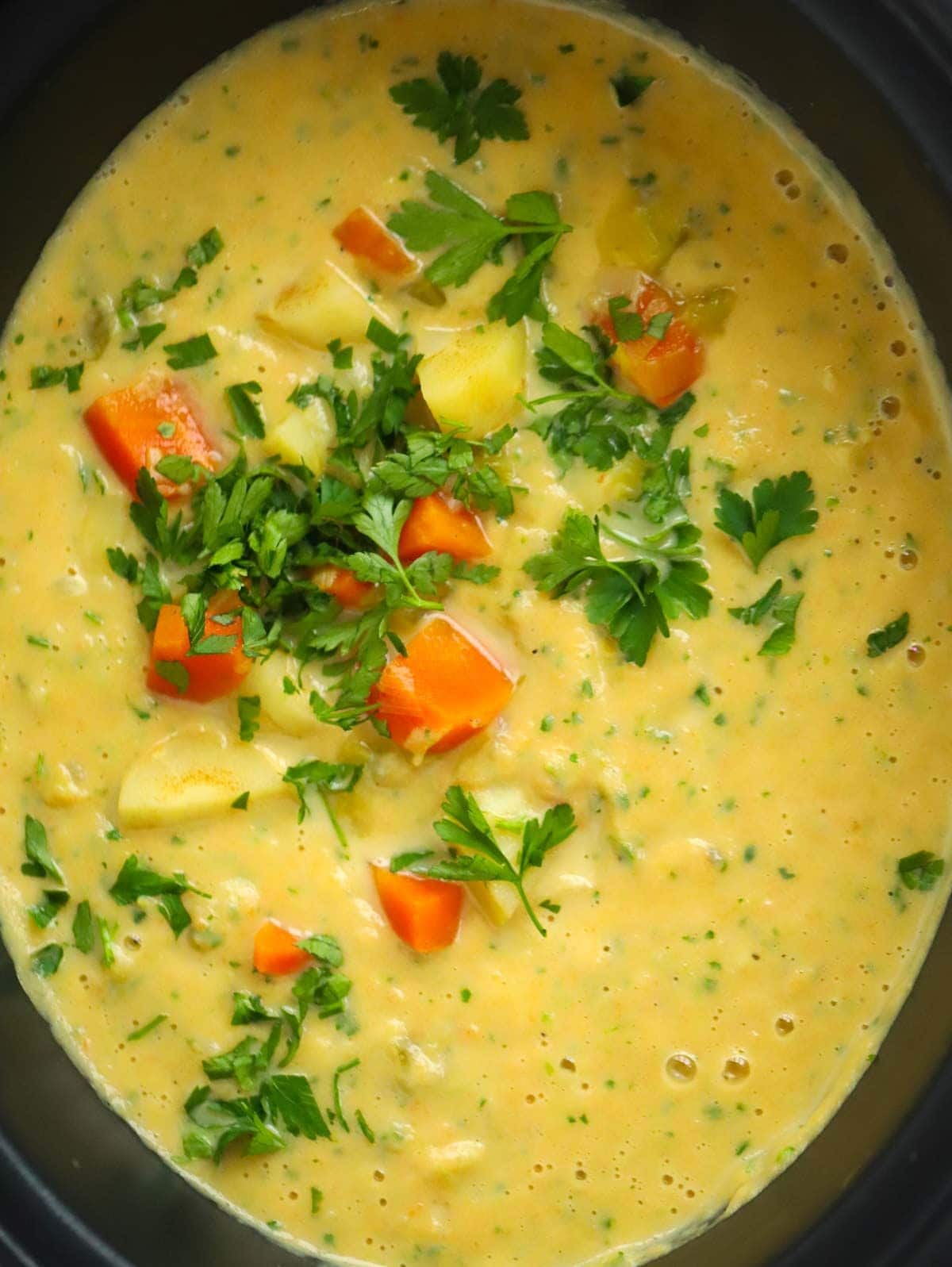 Close up of cooked slow cooker vegetable soup with parsley on top to serve.