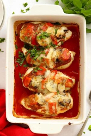Baking dish with pizza topped chicken breast in a tomato sauce.