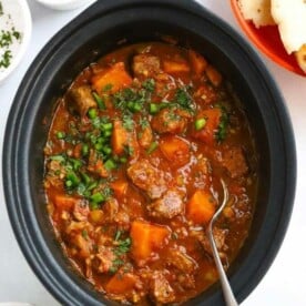 Slow cooker pan filled with cooked lamb curry.