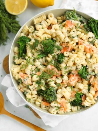 A bowl full of smoked salmon pasta with broccoli and parsley.