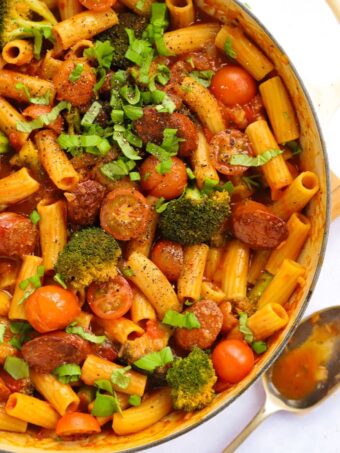 A big pan filled with chorizo pasta, including tomato and broccoli.