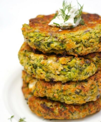 A stack of courgette fritters topped with a little yoghurt and dill.