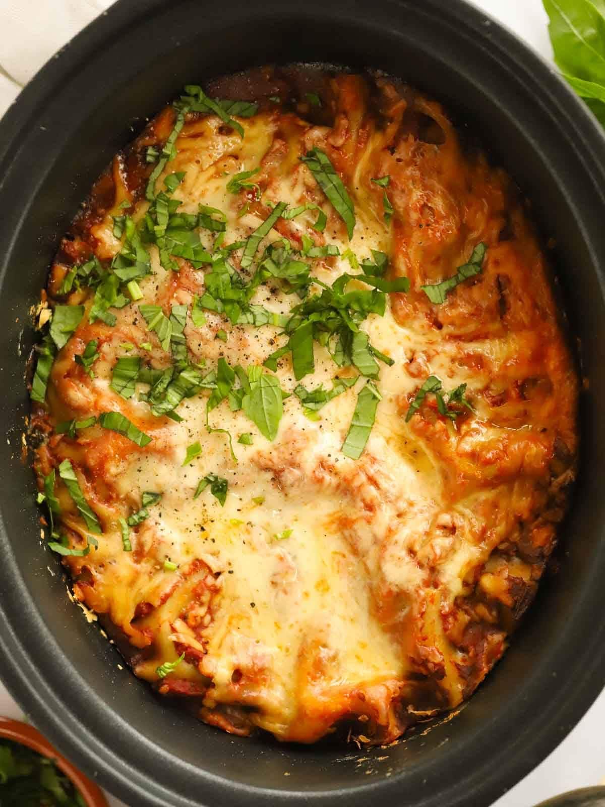 A slow cooker filled with spinach and ricotta slow cooker lasagne, ready to be served.