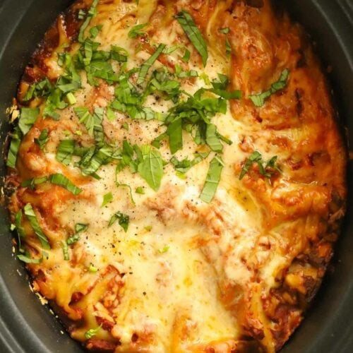 Spinach and ricotta slow cooker lasagne being served with a spoon from the slow cooker.