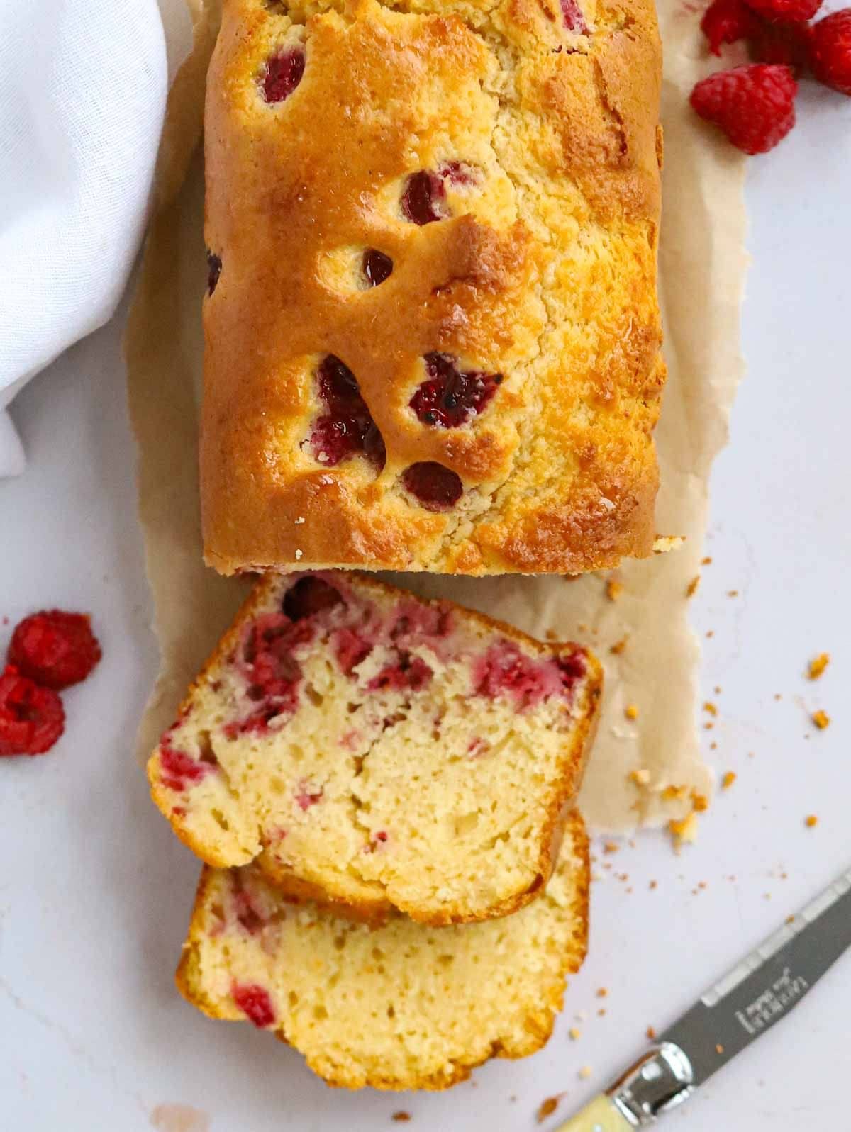 Sliced Yoghurt Cake on a table with raspberries.