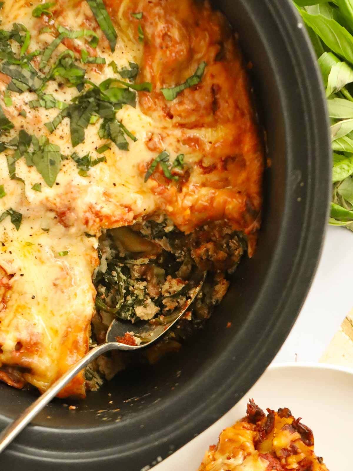 Spinach and ricotta lasagne being spooned out of the slow cooker.