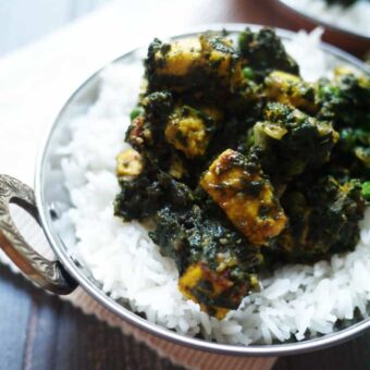 A bowl full of rice and Palak Paneer (spinach and paneer curry) on top.