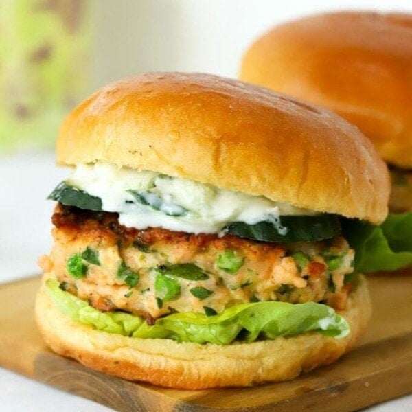 Salmon burgers in a bun on a board.