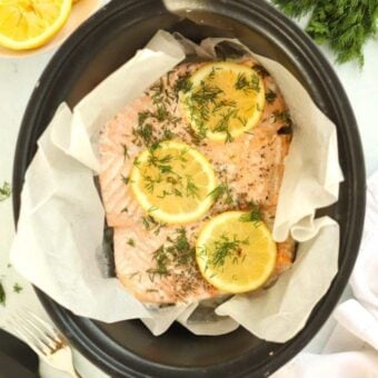 Salmon in the slow cooker topped with lemon, ready to be cooked.